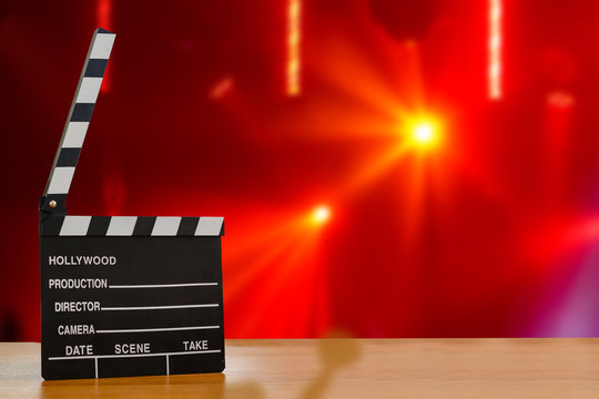 Illuminated Movie Camera With Clapperboard And Film Reel Against Colored Background