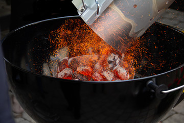 Adding glowing charcoal to the grill