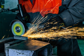 Metal cutting with an angle grinder with a cutting abrasive wheel, sparks in a workshop. - obrazy, fototapety, plakaty