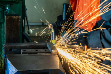 Metal cutting with an angle grinder with a cutting abrasive wheel, sparks in a workshop.