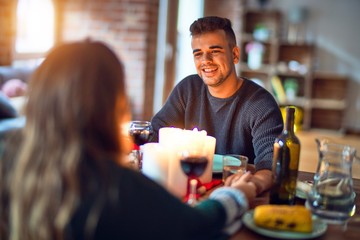 Young beautiful couple smiling happy and confident. Eating food celebrating christmas at home