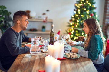 Young beautiful couple smiling happy and confident. Eating food celebrating christmas at home