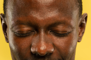 African-american young man's close up portrait on yellow studio background. Beautiful male model with well-kept skin. Concept of human emotions, facial expression, sales, ad. Eyes and cheeks.