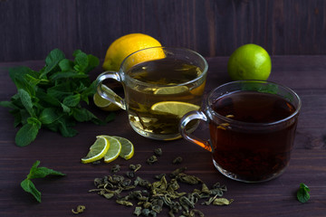 cups of green and black tea with lemon and cinnamon on wooden background and leaves of green mint. healthy lifestyle. cups of tea with lemon and cinnamon on woh lemon and cinnamon on wooden background