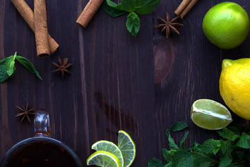 lime and lemon, glass cup of black tea with green mint and cinnamon on a wooden background top view with copy space. healthy lifestyle