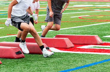 Football players at summer camp running between red barriers