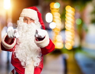 Middle age handsome man wearing Santa Claus costume and beard standing pointing to you and the camera with fingers, smiling positive and cheerful