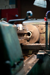 closeup of metallic lathe working against factory industrial interior background
