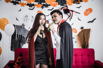 Couple in costume witch and dracula with celebrate Halloween party and drink beer together.