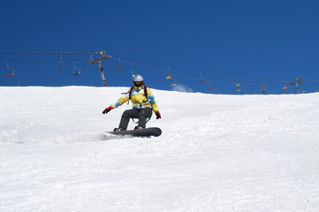 Fototapeta na wymiar Snowboarder descends on snowy ski slope at winter mountain