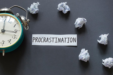 Word Procrastination and retro watch on the dark background.