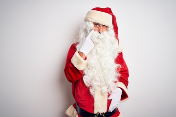 Middle age handsome man wearing Santa costume standing over isolated white background Pointing to the eye watching you gesture, suspicious expression