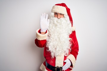 Middle age handsome man wearing Santa costume standing over isolated white background Waiving saying hello happy and smiling, friendly welcome gesture