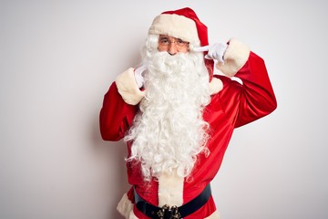 Middle age handsome man wearing Santa costume standing over isolated white background smiling cheerful showing and pointing with fingers teeth and mouth. Dental health concept.