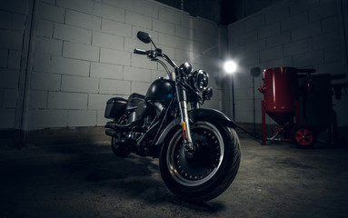 Beautiful shiny bike is parked in dark garage with white walls.