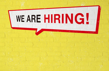 WE ARE HIRING と描かれた煉瓦壁、吹き出し