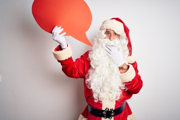 Middle age man wearing Santa costume holding speech bubble over isolated white background cover mouth with hand shocked with shame for mistake, expression of fear, scared in silence, secret concept
