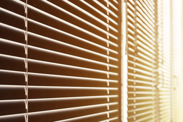 Photo of window of office city building with closed shutters and penetrating sunlight