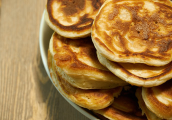 Stack of delicious homemade pancakes on plate, wooden table as background