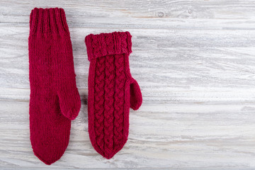 Two warm mittens on an aged white wooden background with space for text