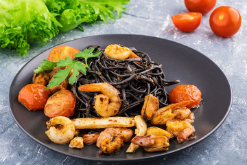 Black spaghetti Nero with seafood and cherry tomatoes on a pillow of green fresh salad as a dietary concept