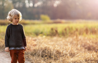 Naklejka na ściany i meble Cute little boy outdoor in the fields 