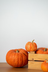 Orange pumpkins in a wooden box on a wooden table on a white background.Halloween, Thanksgiving, Harvest. Selective focus