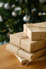 Christmas gifts in craft packaging on a wooden table against the background of a decorated Christmas tree. The concept of Christmas and New Year.