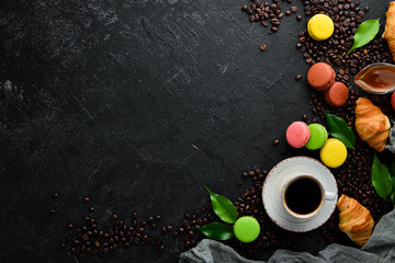 Obraz na płótnie Canvas A cup of coffee with a macaroons cake. On a black stone background. Top view. Free space for your text.