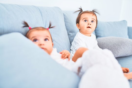 Beautiful infant happy girls playing together at home kindergarten sitting on the sofa