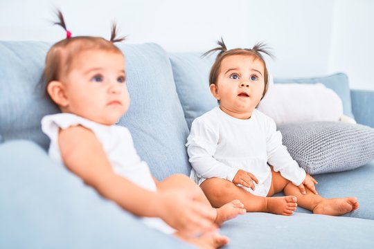 Beautiful infant happy girls playing together at home kindergarten sitting on the sofa