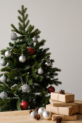 Christmas gifts in craft packaging on a wooden table against the background of a decorated Christmas tree. The concept of Christmas and New Year.