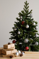 Christmas gifts in craft packaging on a wooden table against the background of a decorated Christmas tree. The concept of Christmas and New Year.