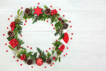 Christmas wreath decoration with loose holly berries and winter flora on rustic wood background...