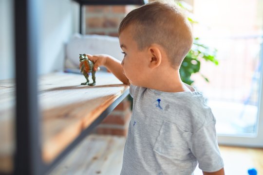 Adorable toddler smiling happy. Standing playing around lots of toys at kindergarten