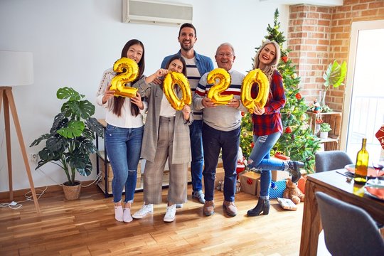 Beautiful family smiling happy and confident. Standing posing with tree holding balloons celebrating New Year at home