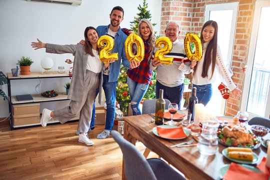 Beautiful family smiling happy and confident. Standing posing with tree holding balloons celebrating New Year at home