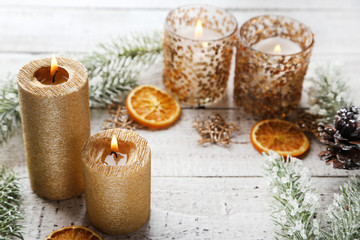 Christmas candles with dry oranges, stars and fir tree branches on white wooden table