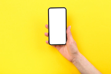 Fototapeta na wymiar Smartphone in female hand on yellow background
