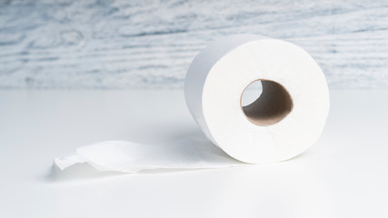 Toilet paper roll on a white table against a background of a wooden structural blue wall. The concept of using bio materials for hygiene
