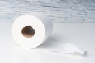 Toilet paper roll on a white table against a background of a wooden structural blue wall as a group...