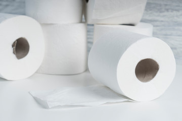 A pile of toilet paper rolls on a white table on a background of blue wall texture. Hygiene products