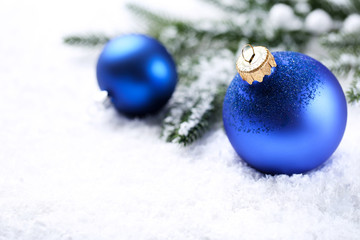 Christmas baubles with fir tree branches on white snow