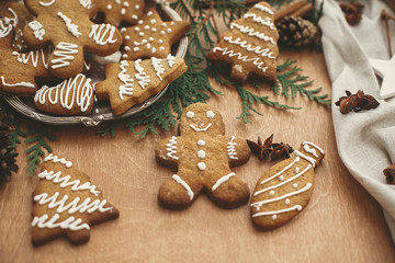 Christmas gingerbread man,  cookies on vintage plate and anise, cinnamon, pine cones and cedar branches on rustic table. Baked traditional gingerbread cookies. Seasons greetings © sonyachny