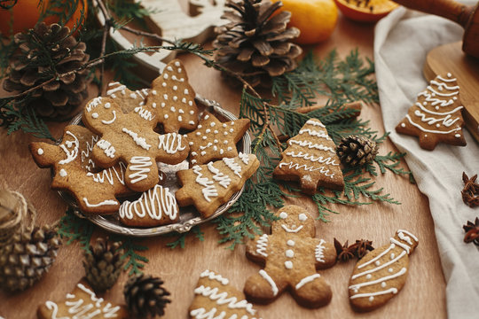 Christmas gingerbread man,  cookies on vintage plate and anise, cinnamon, pine cones and cedar branches on rustic table. Baked traditional gingerbread cookies. Seasons greetings