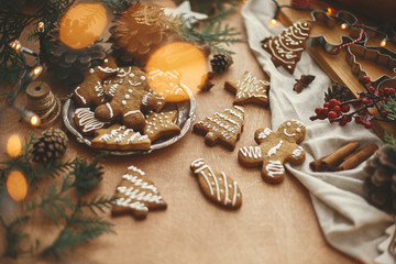 Merry Christmas. Festive gingerbread cookies with anise, cinnamon, pine cones, cedar branches and golden lights bokeh on rustic table. Atmospheric image. Seasons greetings