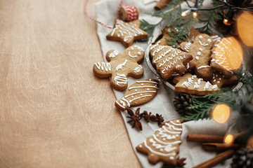 Festive gingerbread cookies with anise, cinnamon, pine cones, cedar branches and golden lights bokeh on rustic table. Space for text. Atmospheric image. Merry Christmas
