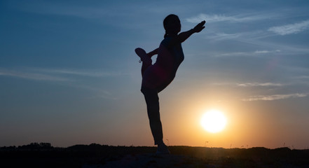 Fototapeta na wymiar Young woman is practicing yoga in natarajasana pose at mountain lake