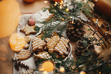 Merry Christmas. Festive gingerbread cookies with anise, cinnamon, pine cones, cedar branches and golden lights bokeh on rustic table. Atmospheric image. Seasons greetings © sonyachny