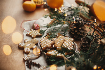 Merry Christmas. Festive gingerbread cookies with anise, cinnamon, pine cones, cedar branches and golden lights bokeh on rustic table. Atmospheric image. Seasons greetings © sonyachny
